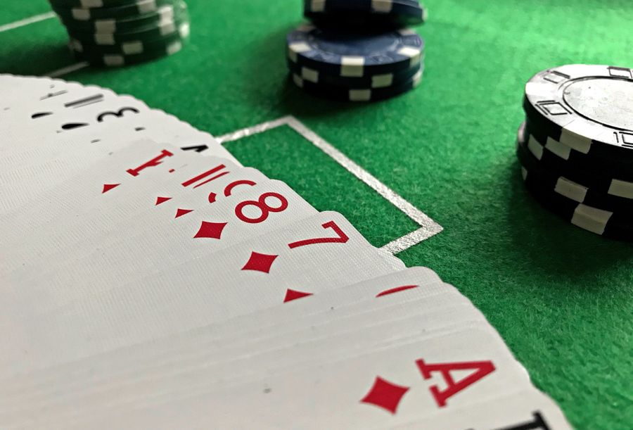 Kartu remi dan chip poker di atas meja hijau